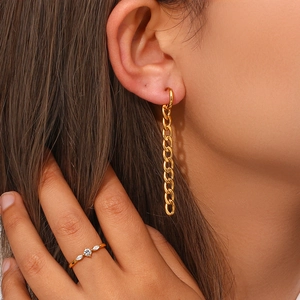 Détail de longues boucles d'oreilles Figaro dorées et bague zircon sur mannequin
