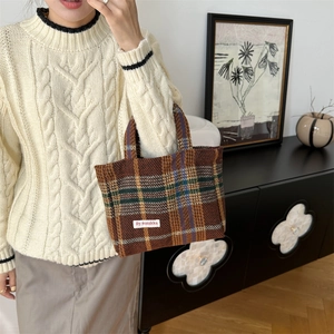 Detail of wool-like plaid texture on a large capacity tote bag with white woven label