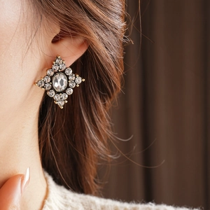 Primo piano di orecchini vintage a rombo con strass scintillanti indossati da una donna