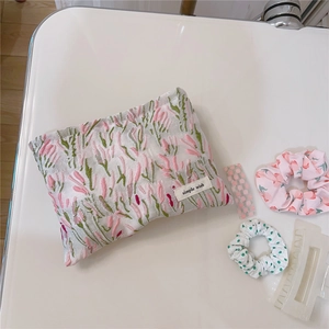 Detailed close-up of pink floral embroidery on canvas makeup bag with logo tag