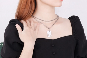 Close-up of double layer silver necklace featuring a rectangular heart cutout pendant