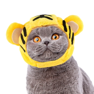 Detail shot of a grey cat wearing a yellow plush tiger hat accessory with stripes