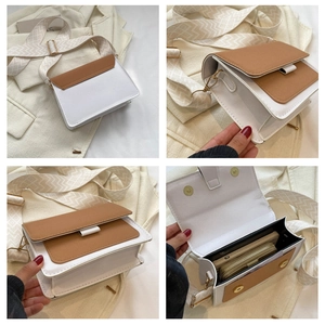 Detail view of white and brown leather crossbody bag with wide printed strap and gold hardware