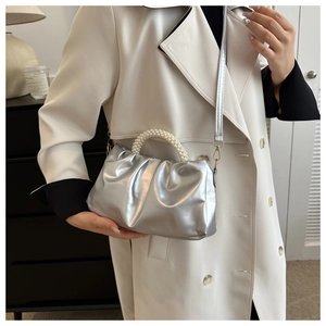 Close-up of metallic silver cloud bag featuring a pearl handle and slim shoulder strap