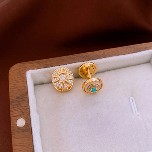 Macro view of gold-plated sunburst earrings with zircon and white mother of pearl