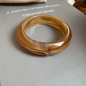 Close-up of amber marble textured resin bangle resting on a grey hardcover book