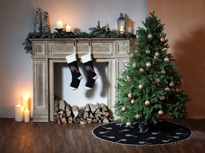 Detail of black knitted Christmas tree skirt and socks with snowflake cane embroidery