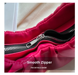 Close-up of smooth metal zipper and pleated faux leather texture on red shoulder bag