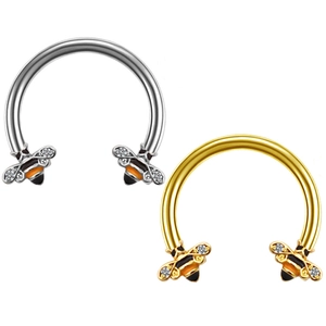 Close-up of gold and silver horseshoe nose rings with diamond-encrusted bee charms