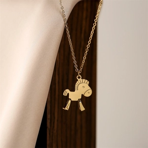 Detail of a polished gold titanium steel necklace featuring a cute pony animal pendant