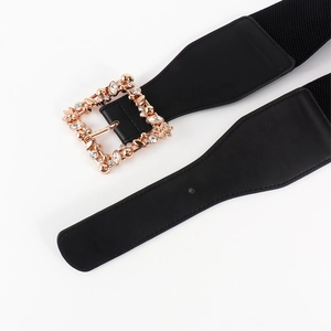 Detailed shot of elastic waist belt with gold square buckle and rhinestone leaf motif