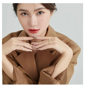 Elegant gold ring with triple zircon stones worn by a model in a brown blazer