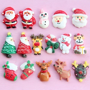 Flat lay of colorful resin Santa, reindeer, and Christmas tree charms on pink wood