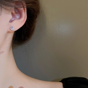 Close-up of elegant silver stud earring with round cubic zirconia on model's ear