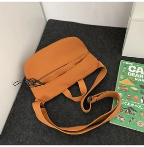 Flat lay of caramel nylon crossbody chest bag on felt background with lifestyle magazine
