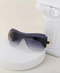 Close-up of rimless Y2K sunglasses with gradient lenses and rhinestone-encrusted gold hinges