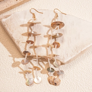 Bohemian tassel earrings with glass beads and shells on a natural stone display