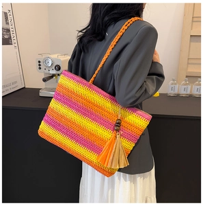 Detail of colorful rainbow striped straw tote bag with braided handles and beaded tassel