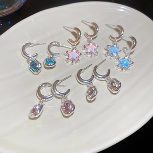 Star-shaped resin pendants and rhinestones earrings displayed on a white ceramic tray