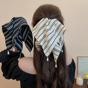 Vue détaillée d'une pince à cheveux à nœud rayé avec pendentif perle sur modèle