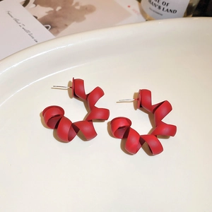 Detailed macro view of matte red spiral twist earrings with premium texture and metal studs