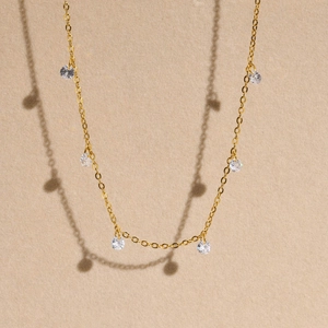 Macro shot of 18K gold plated chain with round zircon gemstones on a beige texture