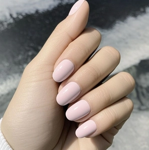 Primer plano de uñas postizas ovales rosa claro brillante con acabado espejo en la mano