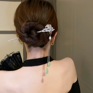 Detail of silver butterfly hair stick with long tassels and green teardrop beads on a bun