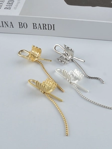 Detail of four gold and silver metal hair clips with chains on a minimalist background