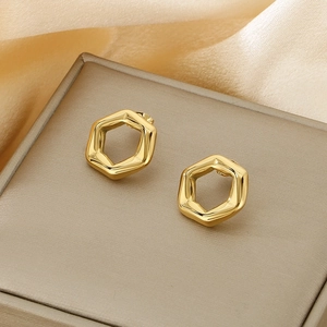 Macro shot of 18K gold plated hexagonal hollow earrings on a satin jewelry box surface