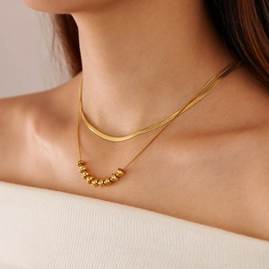 Close-up of double-layer gold snake chain necklace with beads on female neck