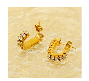 Detail of vintage gold U-shaped earrings with double-row zircon inlay on textured glass