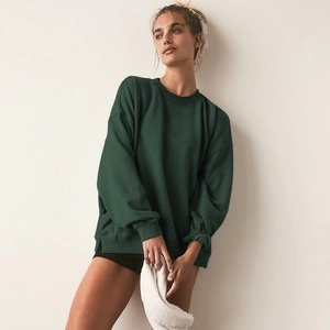 Close-up of the ribbed cuffs and cotton texture of a dark green crewneck sweatshirt