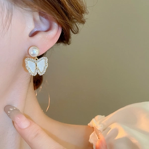 Detail of elegant butterfly pearl earring with zircon inlay and gold plating