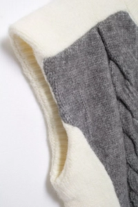 Close-up of knit texture and gray contrast trim on the sleeve of white vest