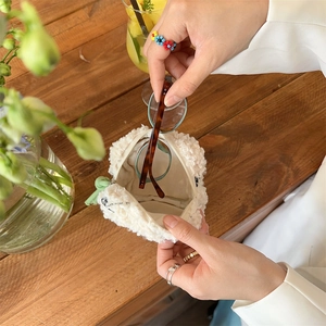 Putting tortoiseshell glasses into a large white plush lamb wool cosmetic storage pouch