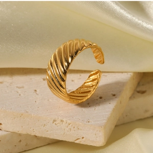Macro detail of golden ribbed open ring on a stone pedestal with elegant silk fabric