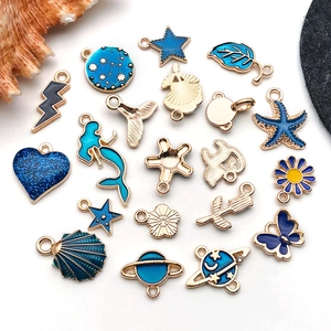 Macro detail of blue enamel ocean and star pendants with gold-plated alloy finish