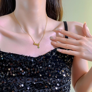 Gold LOVE letter necklace with green heart pendant worn by model in black sequin dress