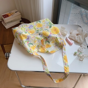 Detailed close-up of a floral cotton tote bag on a white table with daily accessories