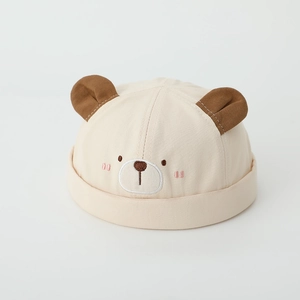 Close-up of baby beige docker hat with bear ears and detailed facial embroidery