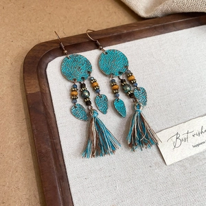 Detailed close-up of Bohemian flower tassel earrings with turquoise discs and leaf charms