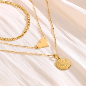 Collana multistrato dorata con catena grumetta, ciondolo a cuore e medaglia occhio