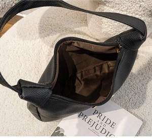 Interior view of black hobo bag with litchi texture and dark brown lining detail