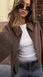 Detail of a brown cropped zip-up wool jacket styled with a white tee and blue jeans