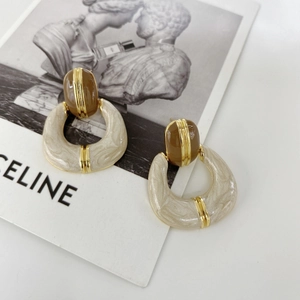 Detail of vintage French gold-plated enamel earrings with brown oval and cream ring