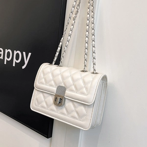Close-up of white quilted leather chain bag with silver clasp and flap detail