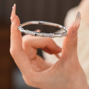 Detail of silver bamboo joint bangle with pavé zircons held by hand in soft light