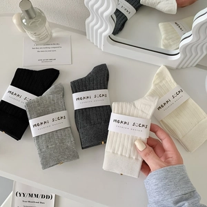 Detail view of five pairs of ribbed cotton mid-calf socks in various neutral tones