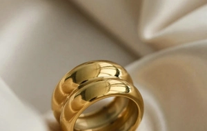 Detail of 18K gold double-layered chunky ring on soft beige silk background